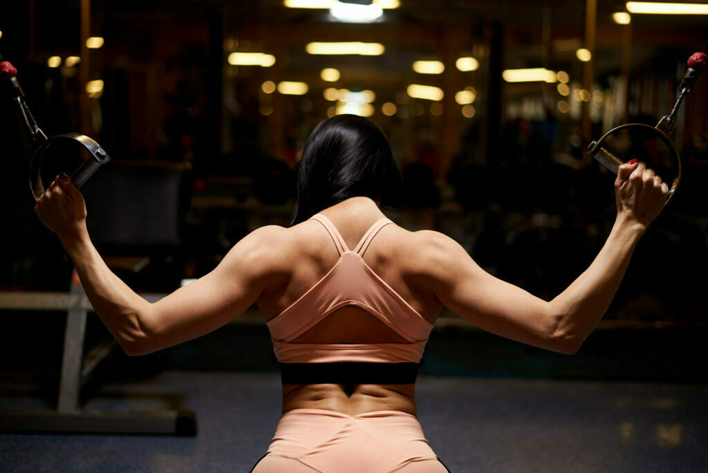Kobieta na siłowni wykonuje trening siłowy. 5 mitów treningowych.